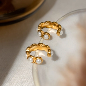 Macro view of 18k gold plated wave-textured C-shape earrings with white round pearls