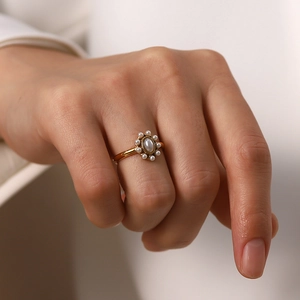 Detailed view of an elegant gold ring featuring a central pearl surrounded by smaller pearls