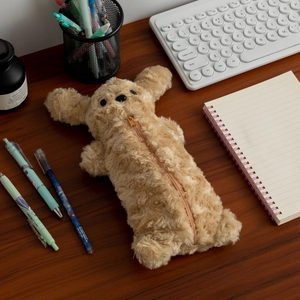 Trousse chiot en peluche bouclée sur un bureau en bois avec clavier et papeterie