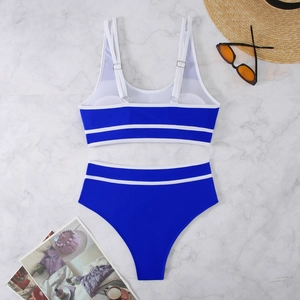Flat lay of royal blue bikini with white trim on marble background with summer props