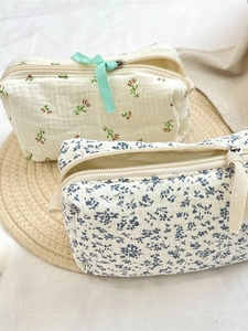 Quilted makeup bags with blue floral and vintage brown embroidery on woven mat