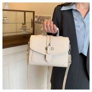 Close-up of beige PU leather handbag with grainy texture and adjustable shoulder strap