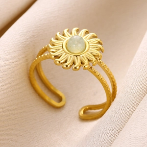 Detailed macro shot of a gold sunburst ring featuring a light green gemstone on a beige fabric