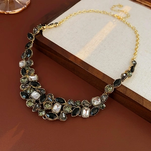 Détail d'un collier doré vintage avec cristaux en forme de larme sur un plateau