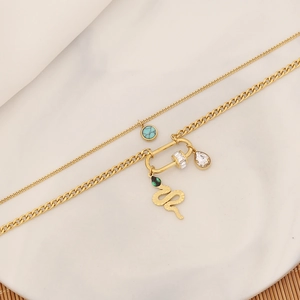 Close-up of double layer gold necklace with turquoise, snake, and crystal charms