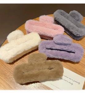 Flat lay of large plush square hair claws in five soft colors on a wooden table