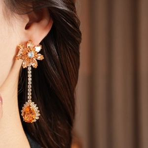Detailed close-up of vintage flower tassel earring with orange zircon on model