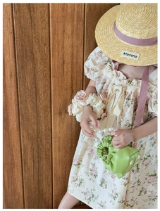 Detail of girl holding a green pleated handbag with a pearl handle in a natural setting