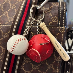 Detailed view of mini baseball, leather glove, and wooden bat keychain hanging on bag