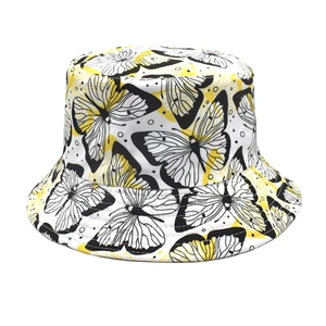 Detail showing white bucket hat with butterfly print and yellow accents and stitched brim