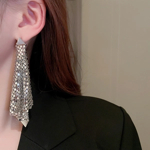 Gros plan de boucles d'oreilles triangulaires argentées à franges avec un design en maille