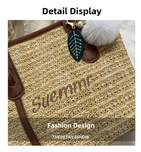 Close-up of woven straw tote bag with brown leather handles and decorative charms