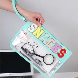 Transparent PVC makeup bag with glitter SNACKS letters and light blue wrist strap handle