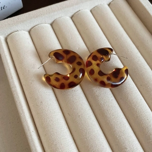 Macro shot of leopard print resin hoop earrings on beige velvet jewelry display box