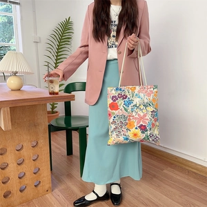 Sac cabas floral en toile avec doubles anses en corde porté par un mannequin en intérieur