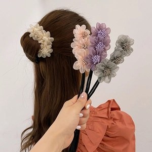 Dettaglio di accessori per chignon a fiori in tessuto beige, rosa, viola e grigio