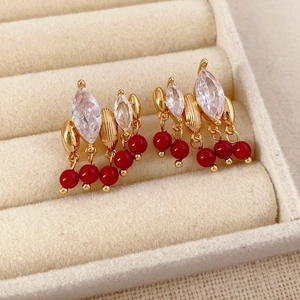 Primo piano di orecchini vintage dorati con nappe rosse e cristalli lucidi