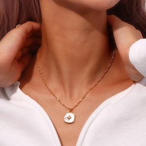 Close-up of golden starburst necklace with shell inlay worn by a model