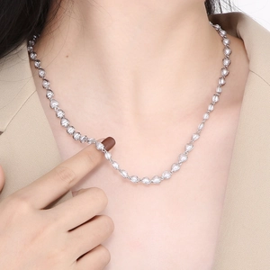 Detailed view of a silver heart-link necklace worn by a model in a beige suit jacket