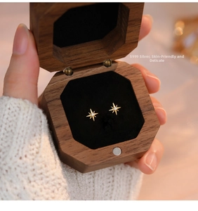 Macro shot of S999 silver gold star stud earrings with zircon in a wooden gift box