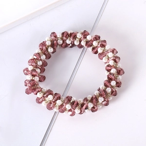 Macro detail of hand-woven hair tie with purple faceted beads and elegant white pearls