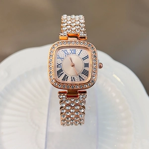 Detail of luxury gold women's square watch with rhinestones on ceramic plate
