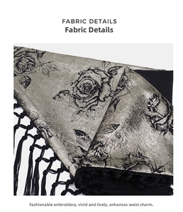 Macro view of silver satin fabric with black rose patterns and long tassel fringe details