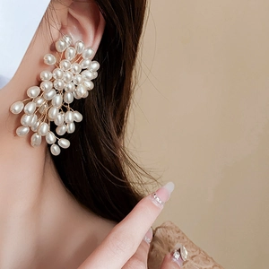 Détail de boucles d'oreilles en perles avec grappes de fleurs et pompons raffinés