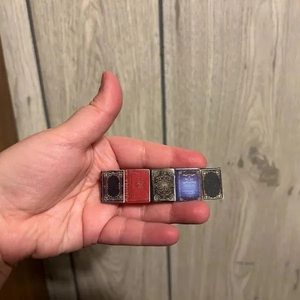 Miniature book charms in five vintage colors held in palm showing small size