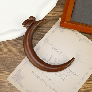 Handcrafted dark sandalwood massage tool with unique crescent shape on vintage background