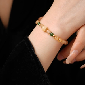 Détail macro de perles ambrées et d'accents dorés en zircon sur un bracelet perlé