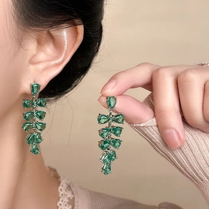 Détail de boucles d'oreilles fleurs en argent avec zircons verts portées par un mannequin