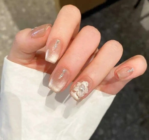 Close-up of pink cat-eye press-on nails with 3D resin flowers and rhinestone accents