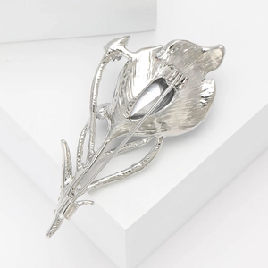 Detail view of the silver leaf brooch pin mechanism on a white geometric background