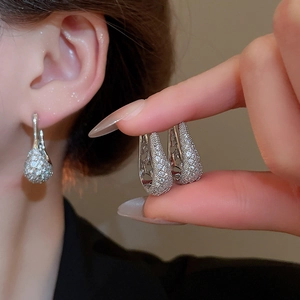 Gros plan de boucles d'oreilles créoles en U argentées avec zircons sertis et éclatant