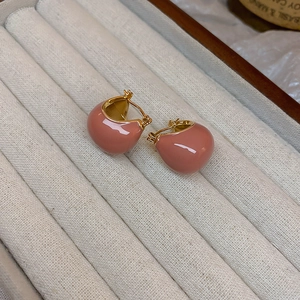 Close-up of pink enamel heart-shaped earrings with gold plating in a jewelry display box