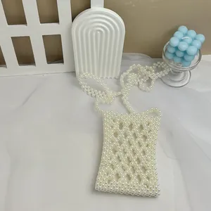 Macro detail of handmade white pearl beaded mini phone bag with hollow diamond pattern