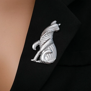 Close-up of a silver vintage cat brooch worn on a classic black blazer lapel