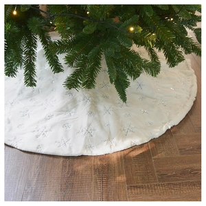Detailed view of plush white Christmas tree skirt with silver snowflake sequins on wood