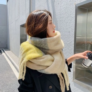 Winter plaid scarf with tassels in yellow beige and grey tones worn by a model outdoor