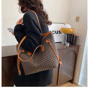 Model carrying a large brown tote bag with vintage geometric print and double straps