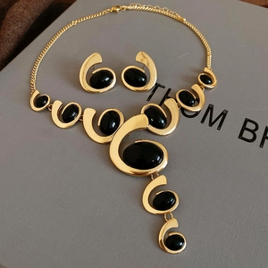 Detail of vintage gold metal jewelry set with oval black gemstones on a gray box