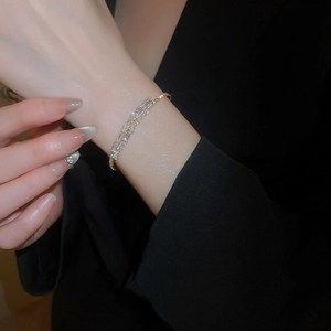 Detail view of gold bangle featuring double-row baguette zircon stones on a wrist
