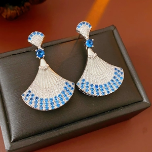 Vintage silver fan-shaped earrings with blue and white gems on a black jewelry box