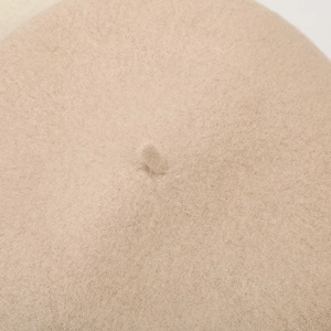 Detailopname van de beige wollen baret met focus op de steel en zachte textuur