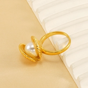 Elegant gold-plated shell ring featuring a natural pearl on a soft textured background