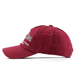 Detail of white 3D embroidery showing Hotel Swan Swimming text on a burgundy cap