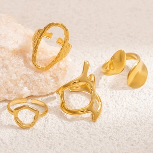 Set of four minimalist gold-plated irregular geometric rings on a stone textured background