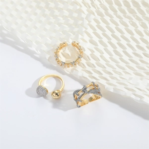 Three elegant gold-plated rings with crystal accents shown on white geometric texture