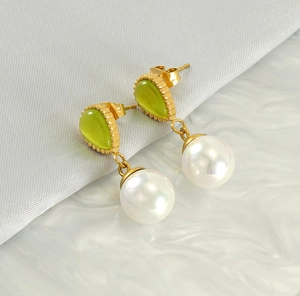 Detail of drop-shaped green opal and large round pearl on elegant gold stud earrings